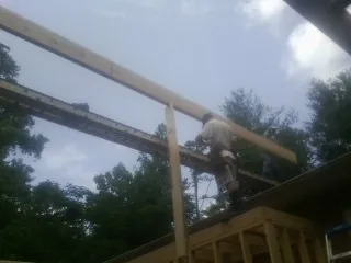 Carpenter setting a ridge beam over a new addition frame — Ice Dam Removal by Roofing Brothers in Laketown