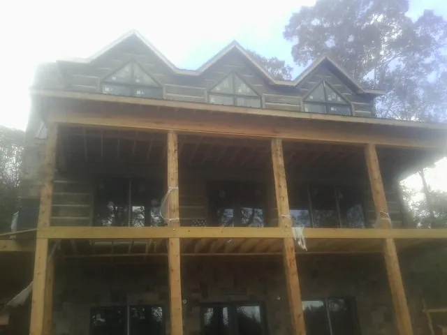 Dormers and porch framing on a large log home under construction — Roof Coating work by our crew in Laketown