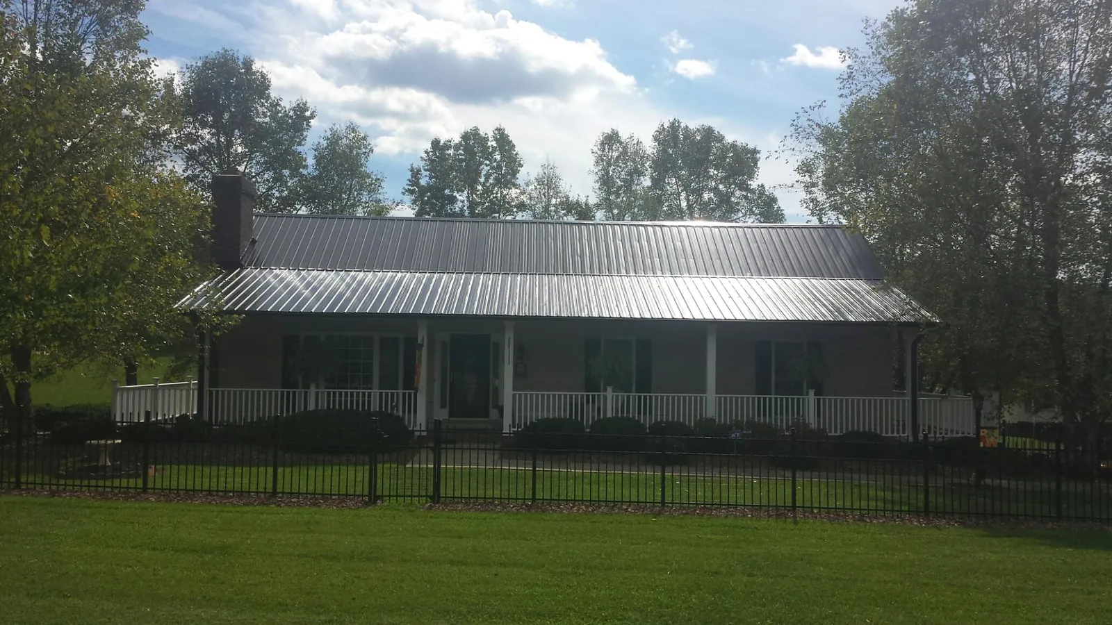 Gray metal roof on a brick ranch with a full width front porch — Gutter Guard Installation work by our crew in Laketown