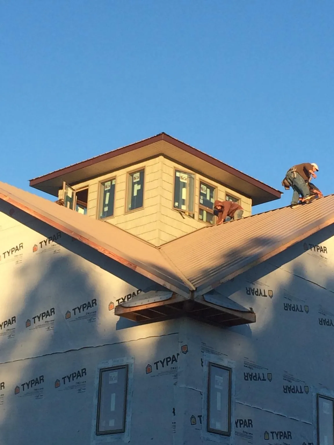 Roofers working around a rooftop cupola on a new metal roof at sunset — Roof Waterproofing in Laketown by Roofing Brothers